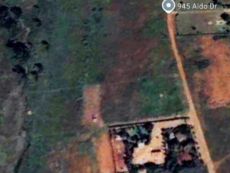 An aerial view of a vacant residential plot showing surrounding terrain and access roads.