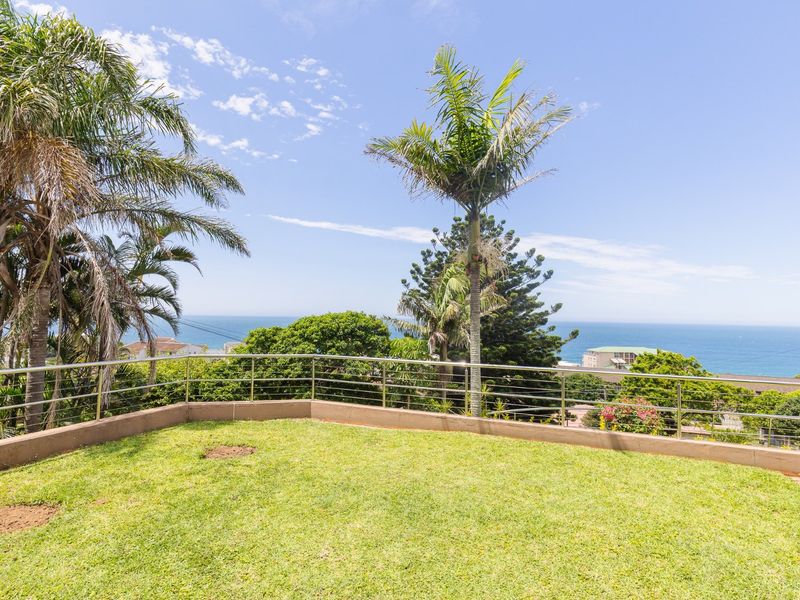 A well-maintained elevated garden area featuring a stainless steel balustrade and expansive ocean views.