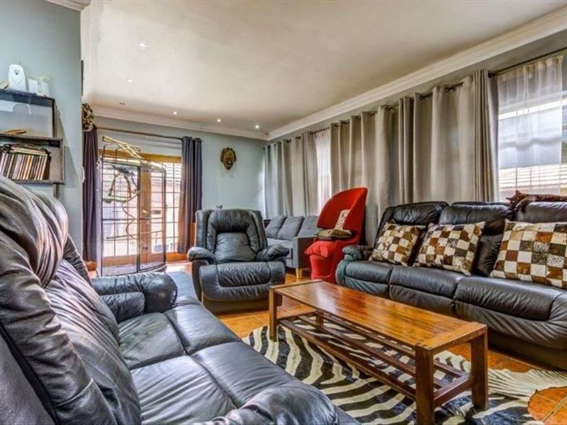 A comfortable living room featuring tiled flooring, recessed downlighting, crown molding, and access to the outdoors via glass-paneled french doors.