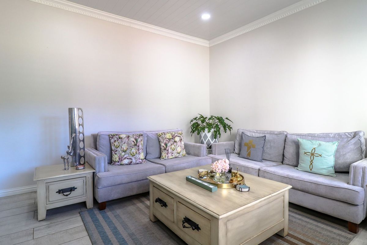 A well-maintained living room featuring neutral walls, crown molding, recessed lighting, and tiled flooring.