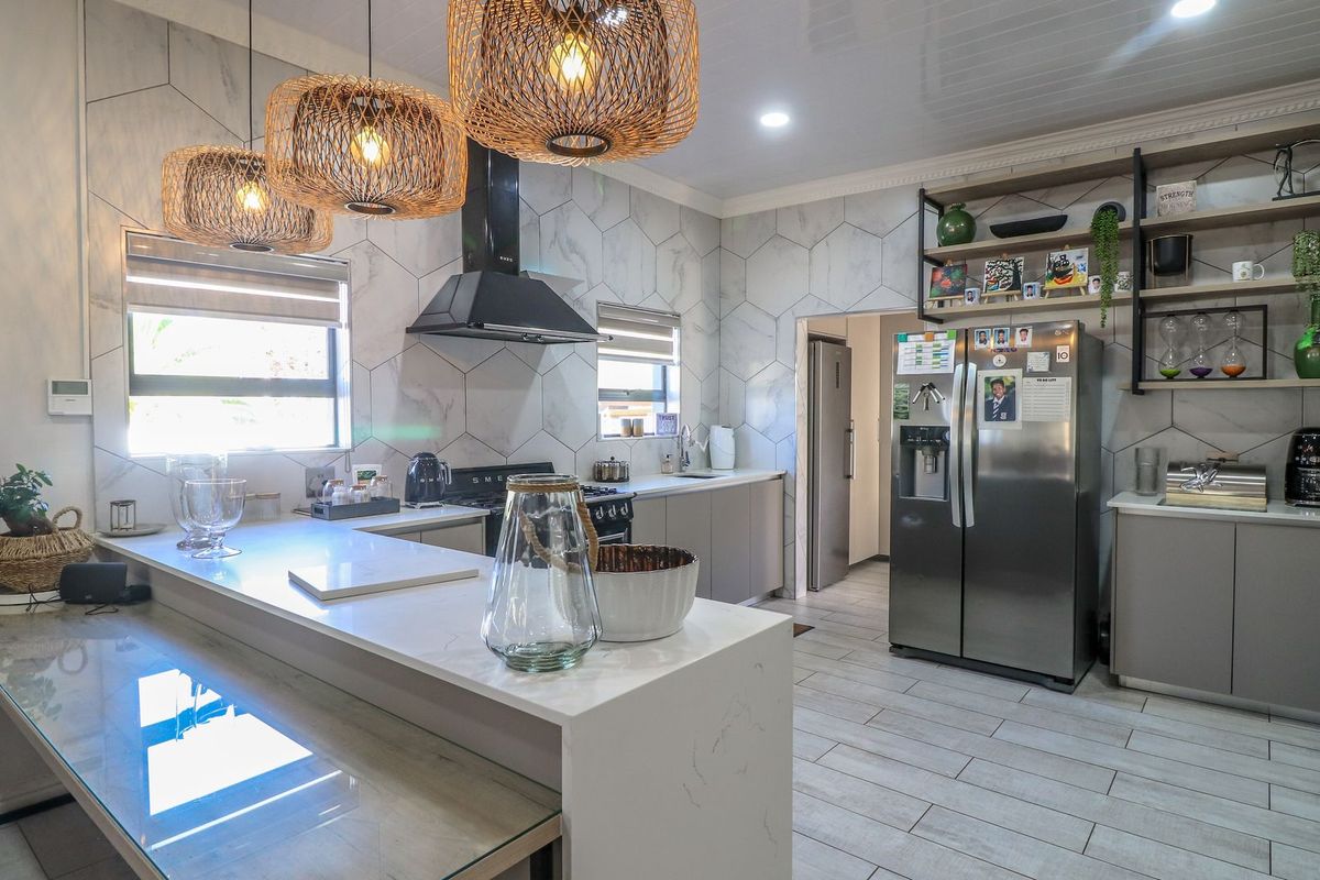 Modern kitchen featuring stone countertops, marble-look hexagonal wall tiles, open shelving, and high-end built-in appliances with a clean, contemporary aesthetic.