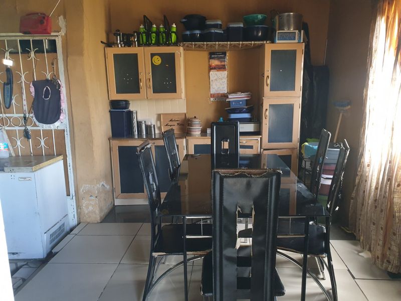 Dining area featuring built-in cabinetry and tiled flooring, showing signs of wear and wall surface deterioration.