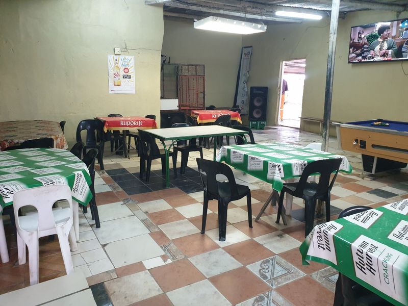 A large, open-plan communal space featuring tiled flooring and exposed ceiling structure, suitable for a social or entertainment area.