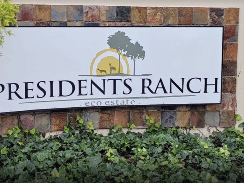 A clear view of the Presidents Ranch eco estate entrance signage featuring stone cladding and surrounding greenery.