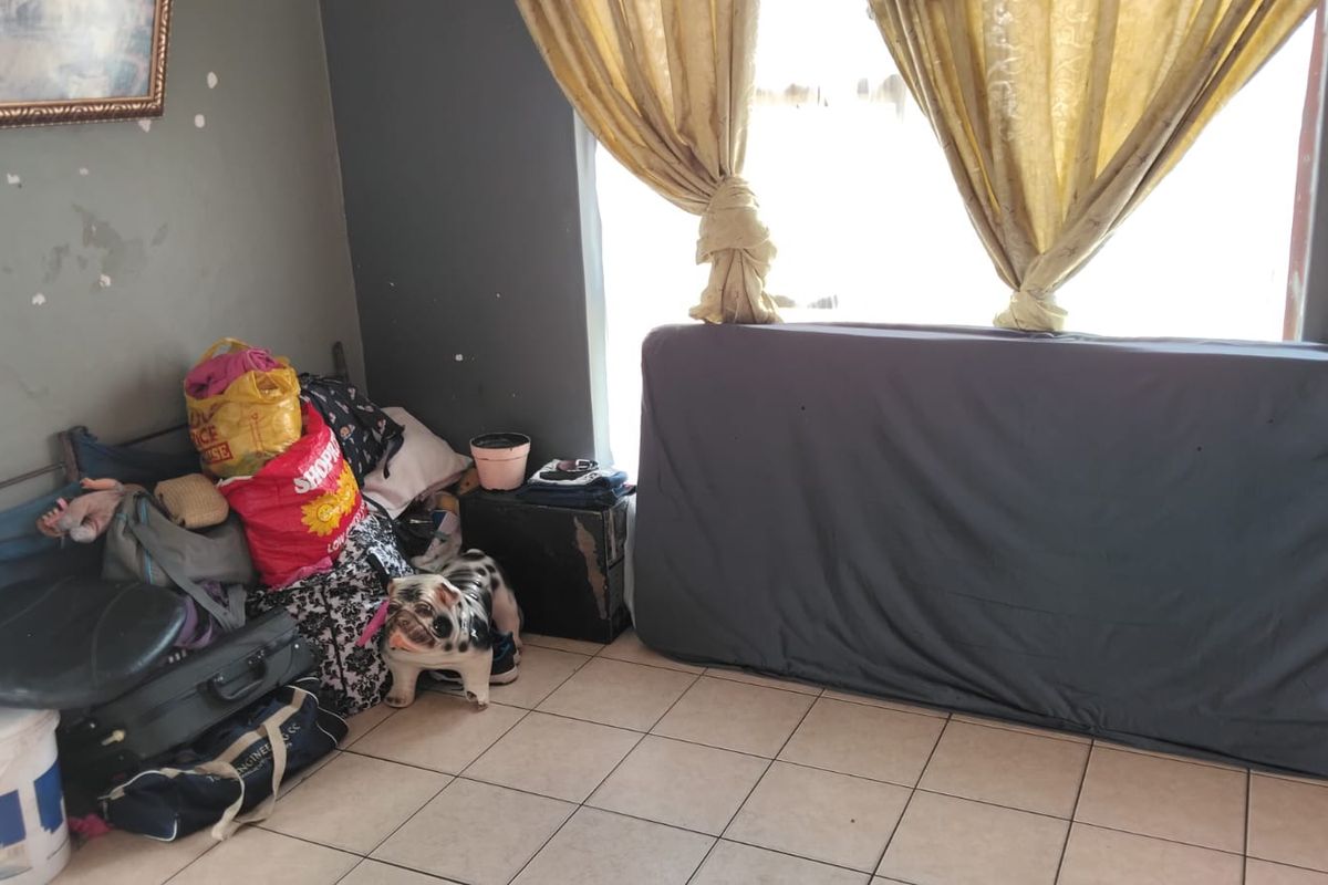 A bedroom space featuring tiled flooring and walls in need of cosmetic repair and repainting.