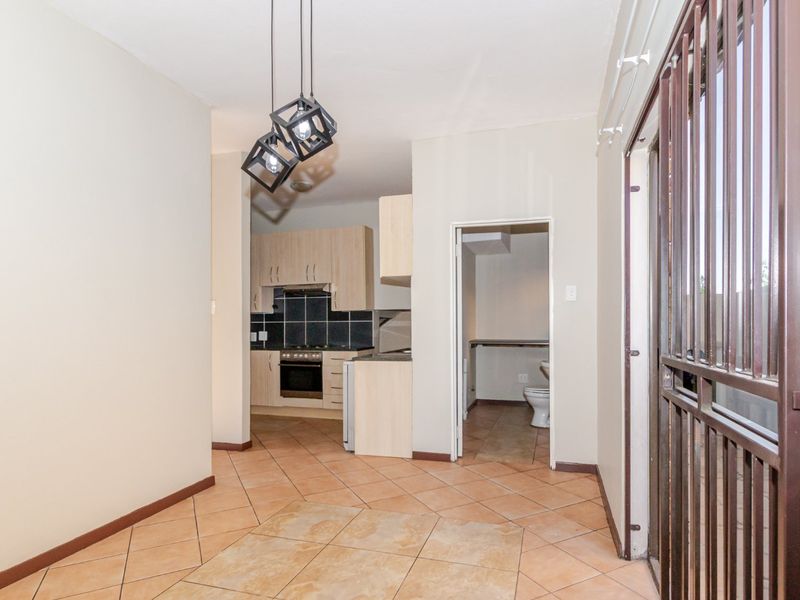 Open plan living area featuring tiled floors, a functional kitchen with built-in cabinetry, and direct access to an adjacent bathroom.