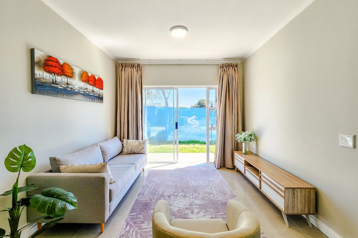 A bright and well-maintained living room featuring tiled flooring and a sliding glass door that provides direct access to the outdoor area.