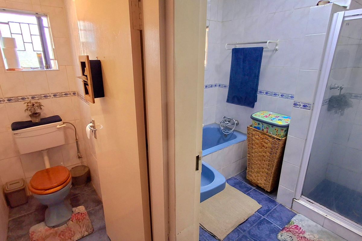 A dated bathroom featuring a blue bathtub, separate shower enclosure, and tiled finishes, offering potential for a modern renovation.