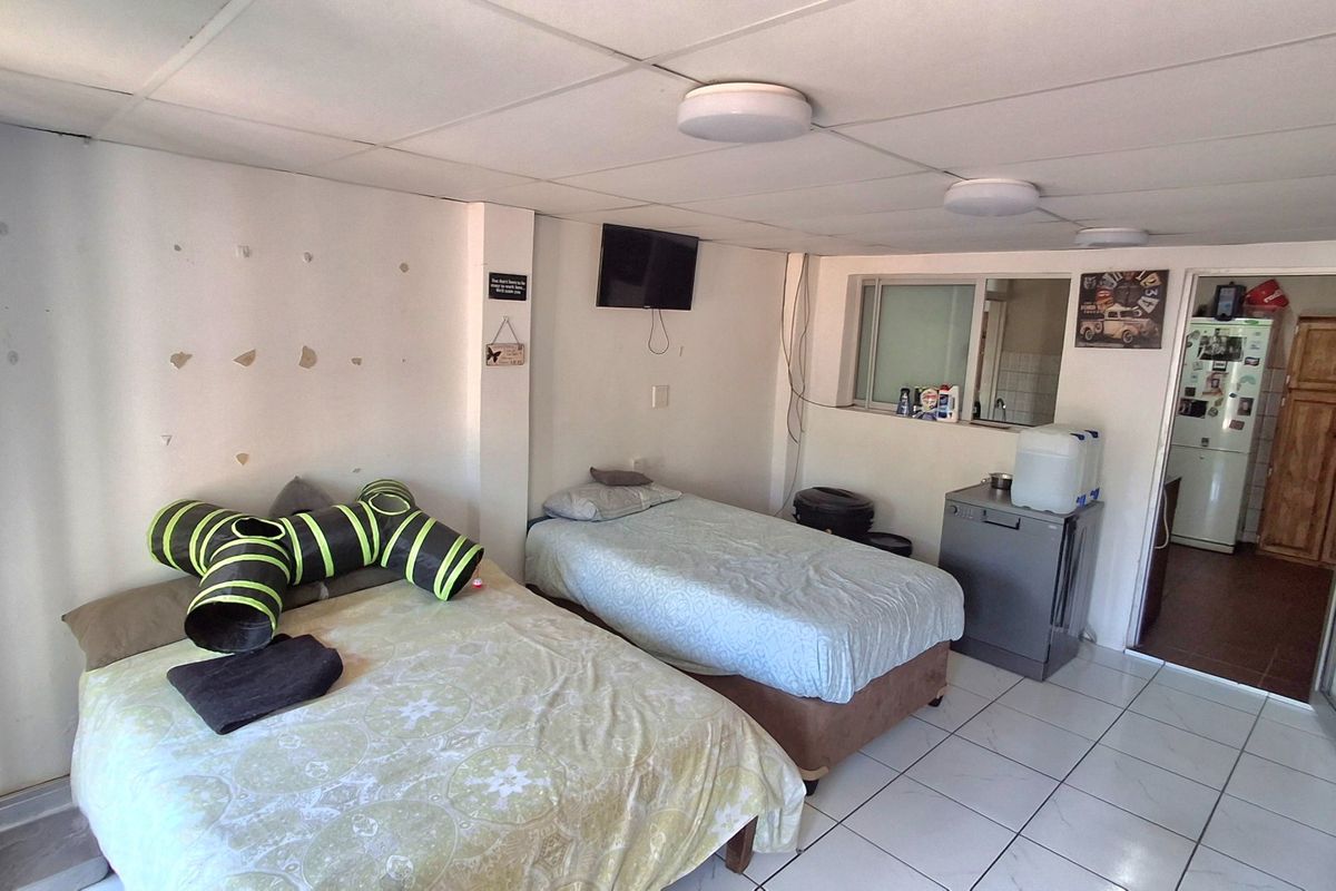 A bedroom featuring tiled flooring and a drop ceiling, currently showing signs of wear including wall surface damage and exposed wiring.