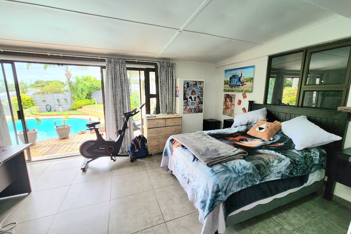 Spacious bedroom featuring large sliding glass doors that open directly onto the pool area, providing ample natural light and seamless indoor-outdoor flow.