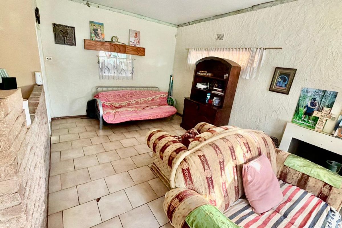 A living room featuring tiled flooring, a fireplace, and textured walls, offering a dated interior space with potential for modernization and renovation.