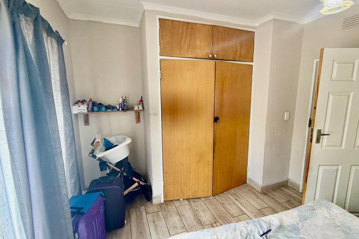 A bedroom featuring wood-look tile flooring and a built-in wooden wardrobe with additional overhead storage space.