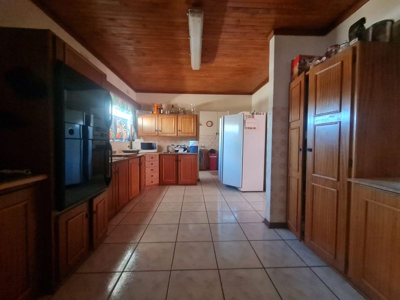 A spacious kitchen featuring extensive wooden cabinetry, tiled flooring, and a traditional wooden ceiling, offering a functional layout with ample storage space.