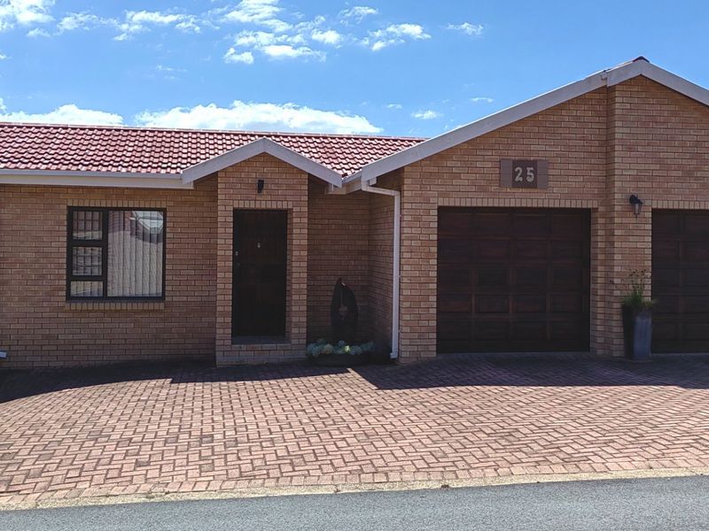 Front elevation of a face brick house featuring a double garage, tiled roof, and a paved driveway.