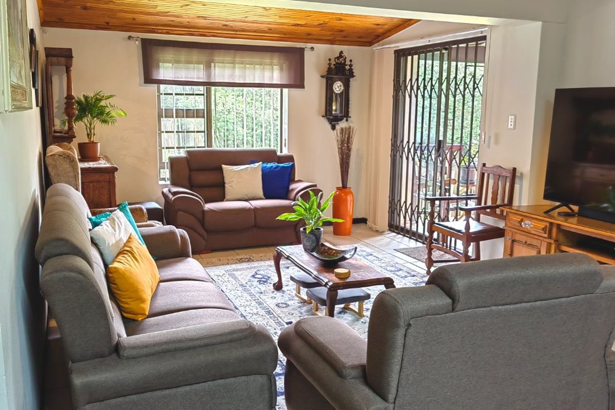 Spacious living area featuring a warm timber-clad ceiling, ceramic tiled flooring, and direct access to the outdoor area through a sliding security gate.