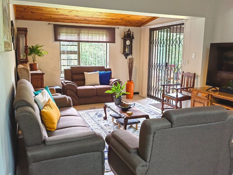 Spacious living area featuring a warm timber-clad ceiling, ceramic tiled flooring, and direct access to the outdoor area through a sliding security gate.