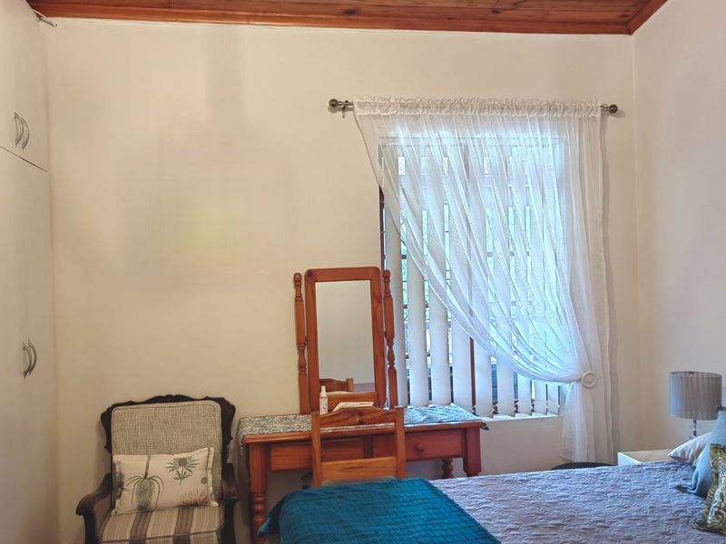 A bedroom featuring a timber-clad ceiling, built-in cupboards, and tiled flooring, offering a cozy and functional living space.