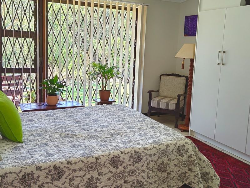 A bedroom featuring built-in wardrobes, tiled flooring, and a sliding glass door with a security gate leading to the exterior.