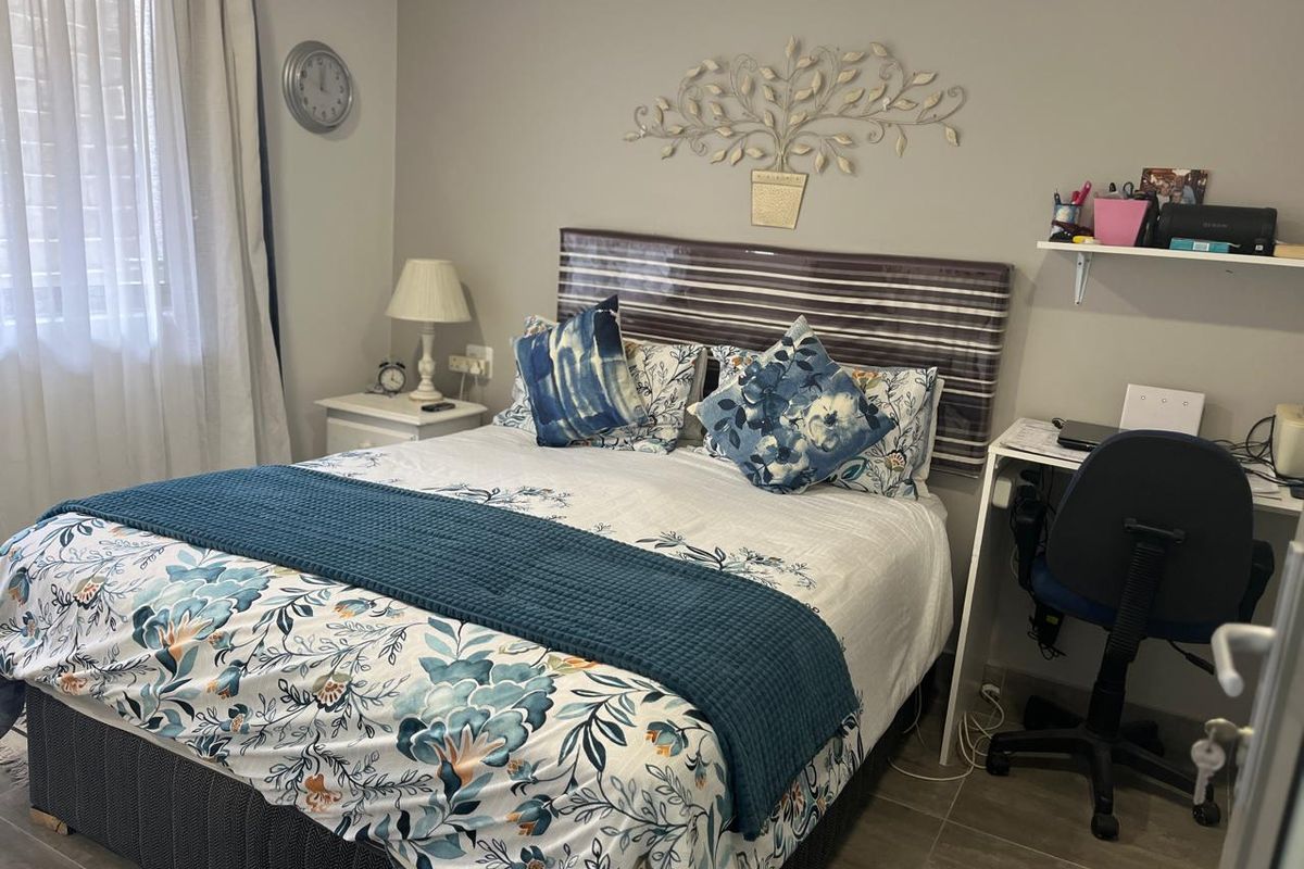 A well-maintained bedroom featuring tiled flooring and neutral wall finishes, providing a comfortable and functional sleeping space.