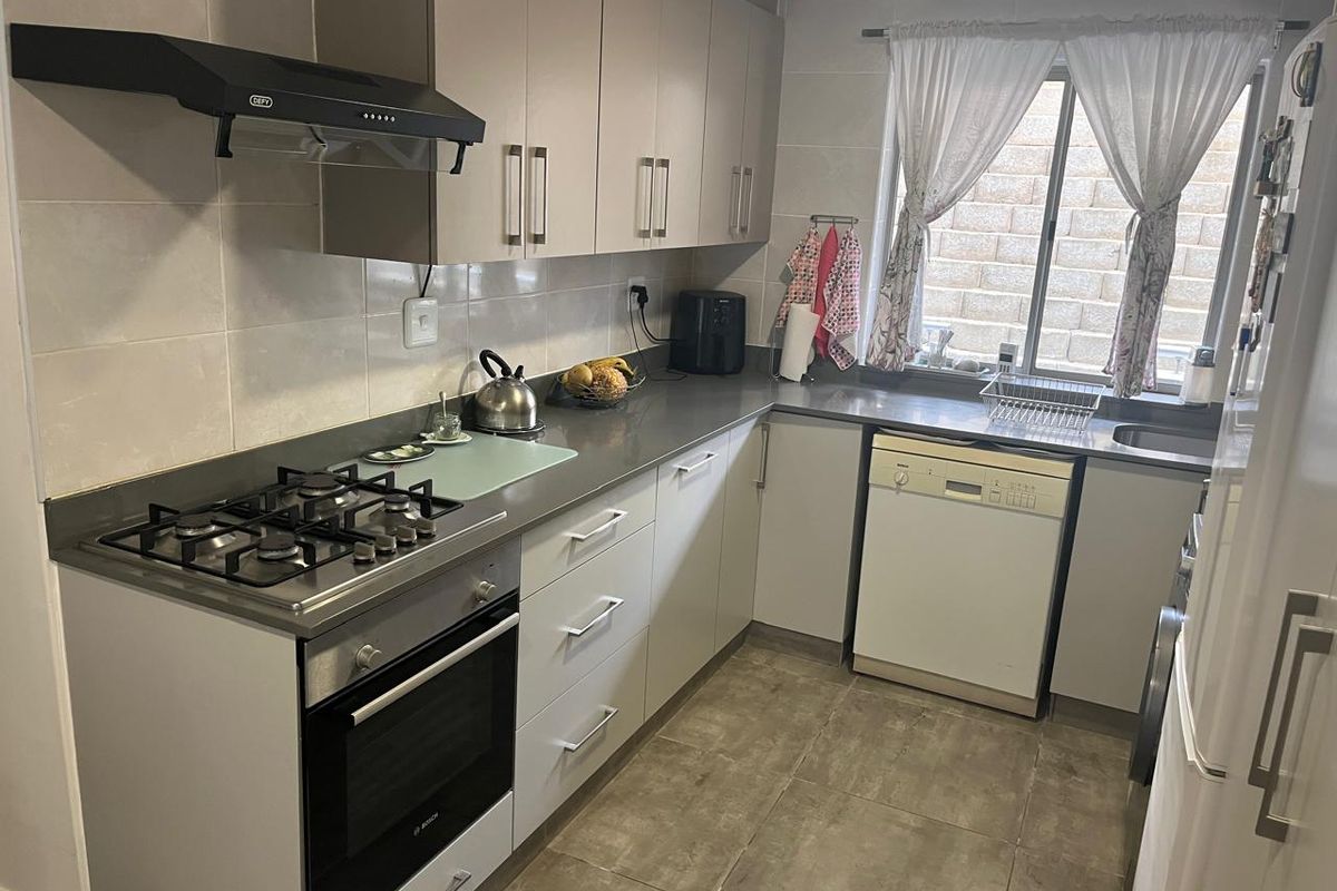 A functional kitchen featuring modern laminate cabinetry, stone countertops, a gas hob, built-in oven, and integrated dishwasher with tiled flooring.