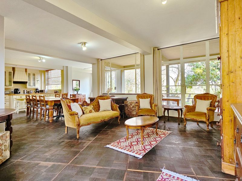 Spacious open-plan living and dining area featuring tiled floors, large windows, and an integrated kitchen with cabinetry.