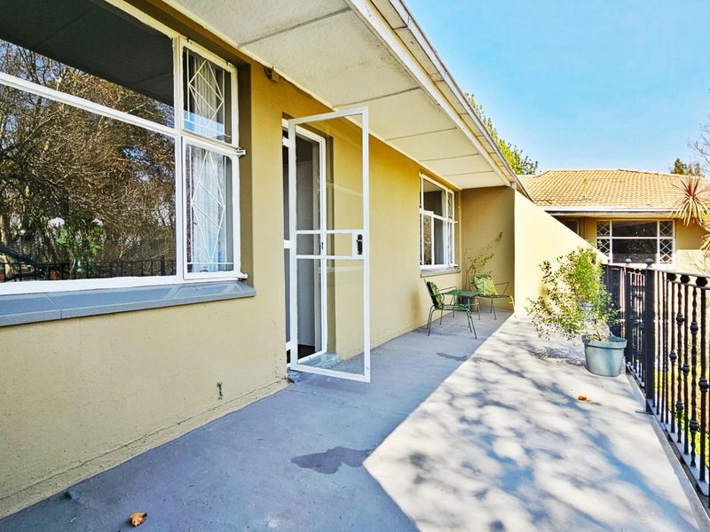 A spacious covered balcony featuring concrete flooring, a security gate, and wrought iron railings, offering an open outdoor area for relaxation.