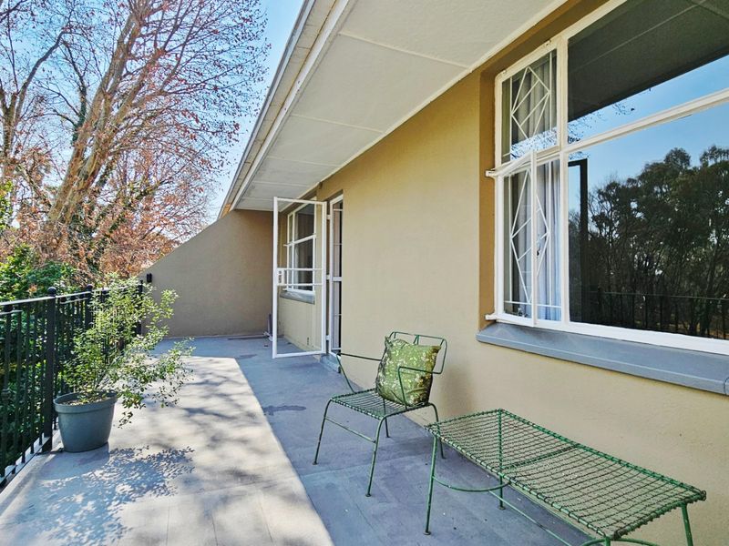 A spacious outdoor balcony featuring tiled flooring, a wrought iron balustrade, and direct access to the interior through a security gate.