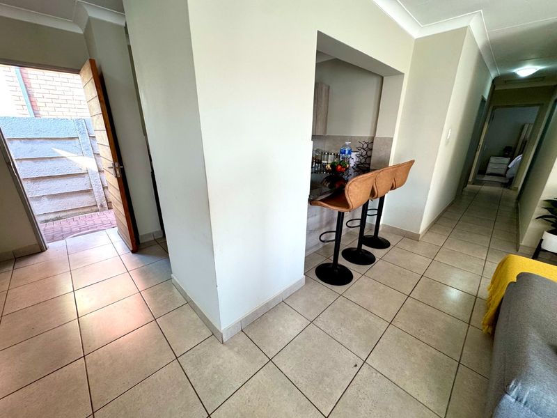 Open plan living area featuring tiled flooring, a breakfast bar counter, and direct access to an exterior courtyard.