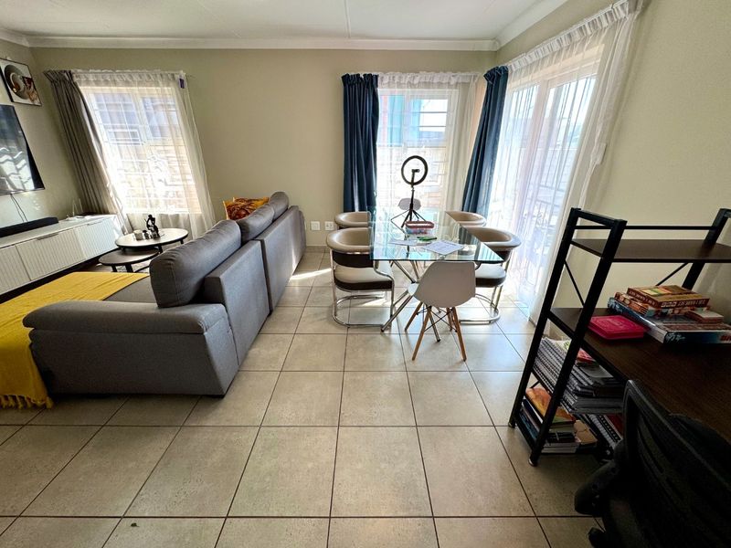 Open-plan living and dining area featuring neutral tiled flooring and large sliding glass doors providing natural light.