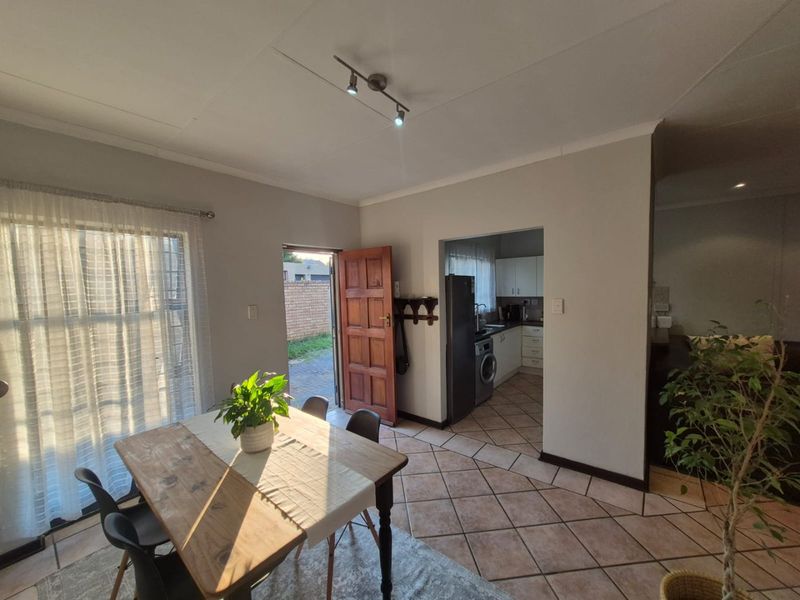 Open plan living and dining area featuring tiled flooring, track lighting, and direct access to the kitchen and exterior entrance.