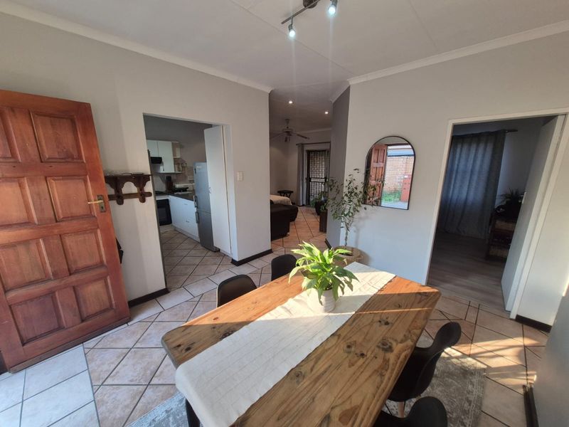 Open plan dining area featuring tiled flooring, track lighting, and access to the kitchen and adjacent living spaces.