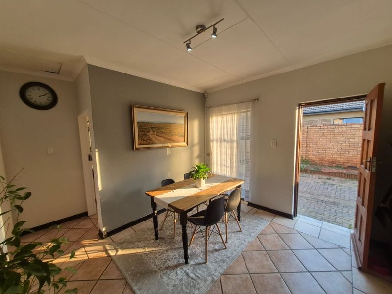 A bright dining area featuring ceramic floor tiles, modern track lighting, and direct access to an outdoor patio through a sliding glass door.