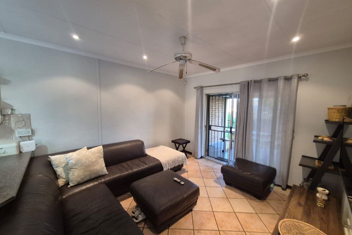 A living room featuring ceramic floor tiles, a ceiling fan, recessed lighting, and a sliding glass door providing access to the outdoor area.