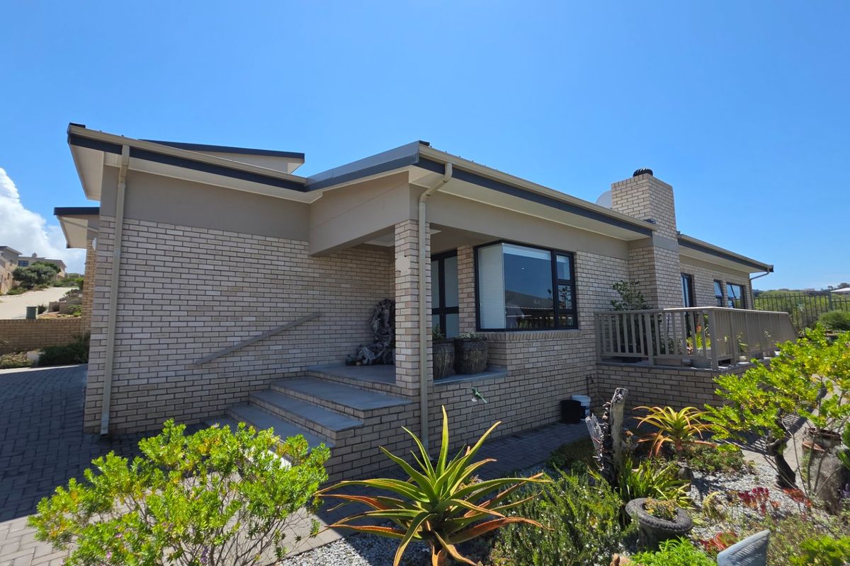Rear view of a brick house featuring a covered patio, timber decking, and a well-maintained landscaped garden area.