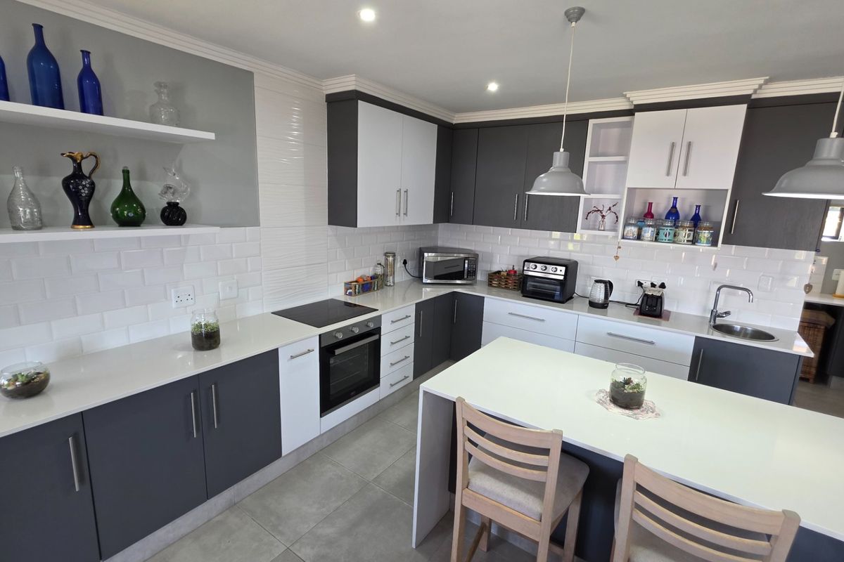 Modern kitchen featuring two-tone cabinetry, quartz countertops, subway tile backsplash, a central island, and integrated appliances with contemporary pendant lighting.
