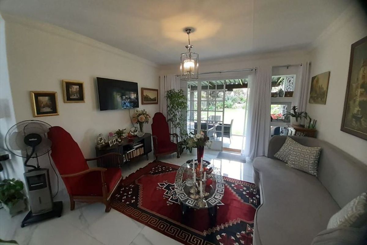 A comfortable living room featuring tiled flooring and a sliding glass door that provides direct access to the outdoor patio and garden area.