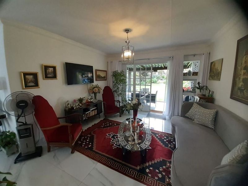 A comfortable living room featuring tiled flooring and a sliding glass door that provides direct access to the outdoor patio and garden area.