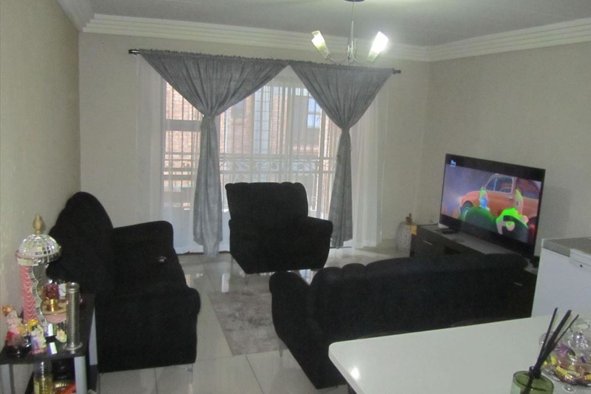 A living room area featuring tiled flooring, ceiling cornice detailing, and a sliding glass door providing access to an outdoor space.