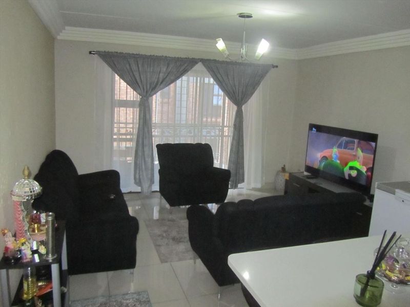 A living room area featuring tiled flooring, ceiling cornice detailing, and a sliding glass door providing access to an outdoor space.