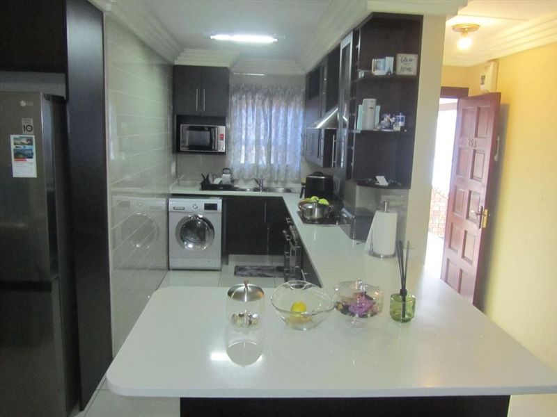 A functional kitchen featuring dark cabinetry, stone countertops, integrated appliances, and a breakfast bar, providing a practical and efficient workspace.
