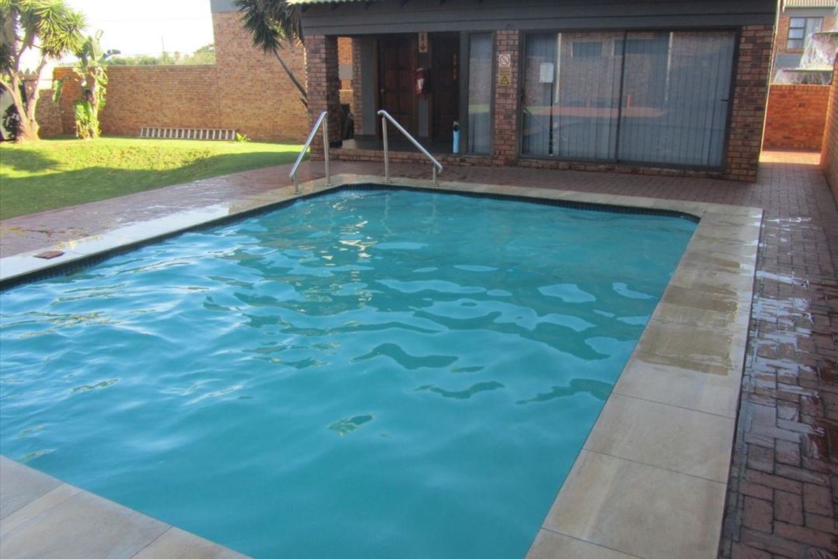 Outdoor swimming pool area featuring paved surround, metal handrails, and direct access to the adjacent building structure.