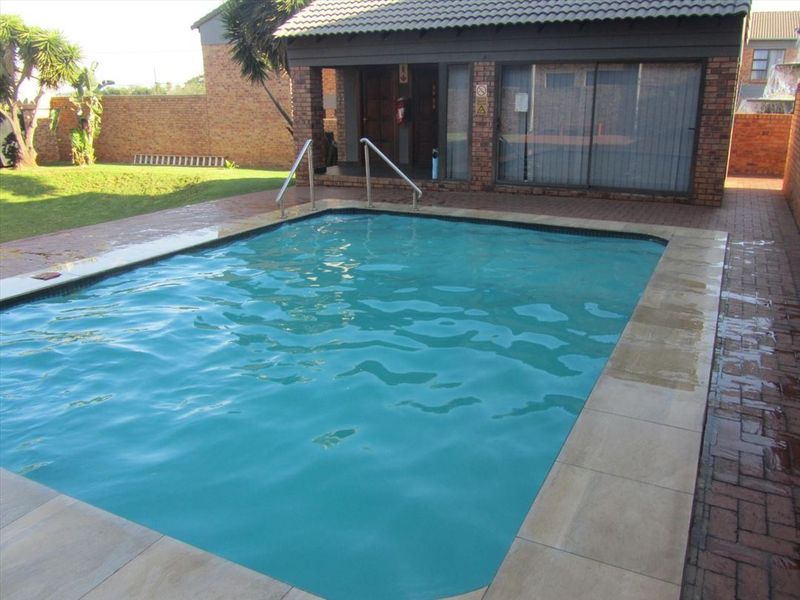 Outdoor swimming pool area featuring paved surround, metal handrails, and direct access to the adjacent building structure.