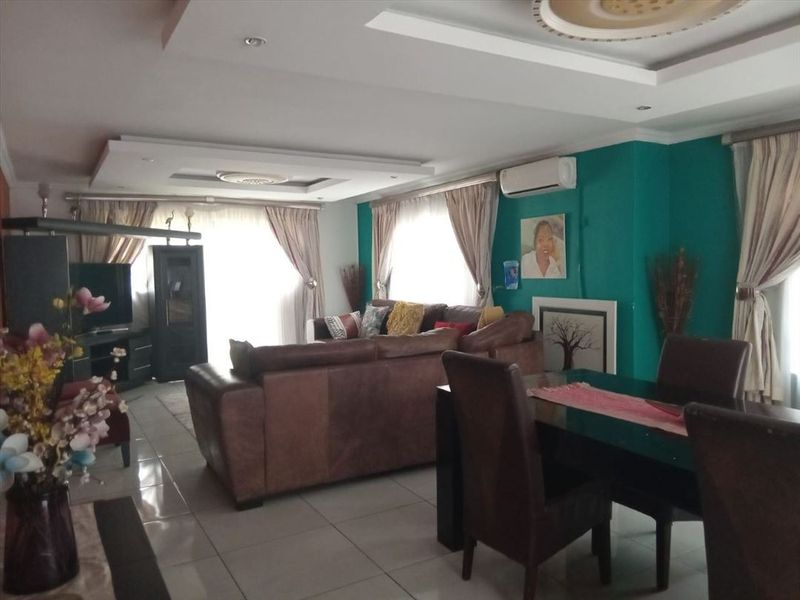 Spacious open-plan living and dining area featuring tiled flooring, recessed ceiling details with cove lighting, and a wall-mounted air conditioning unit.