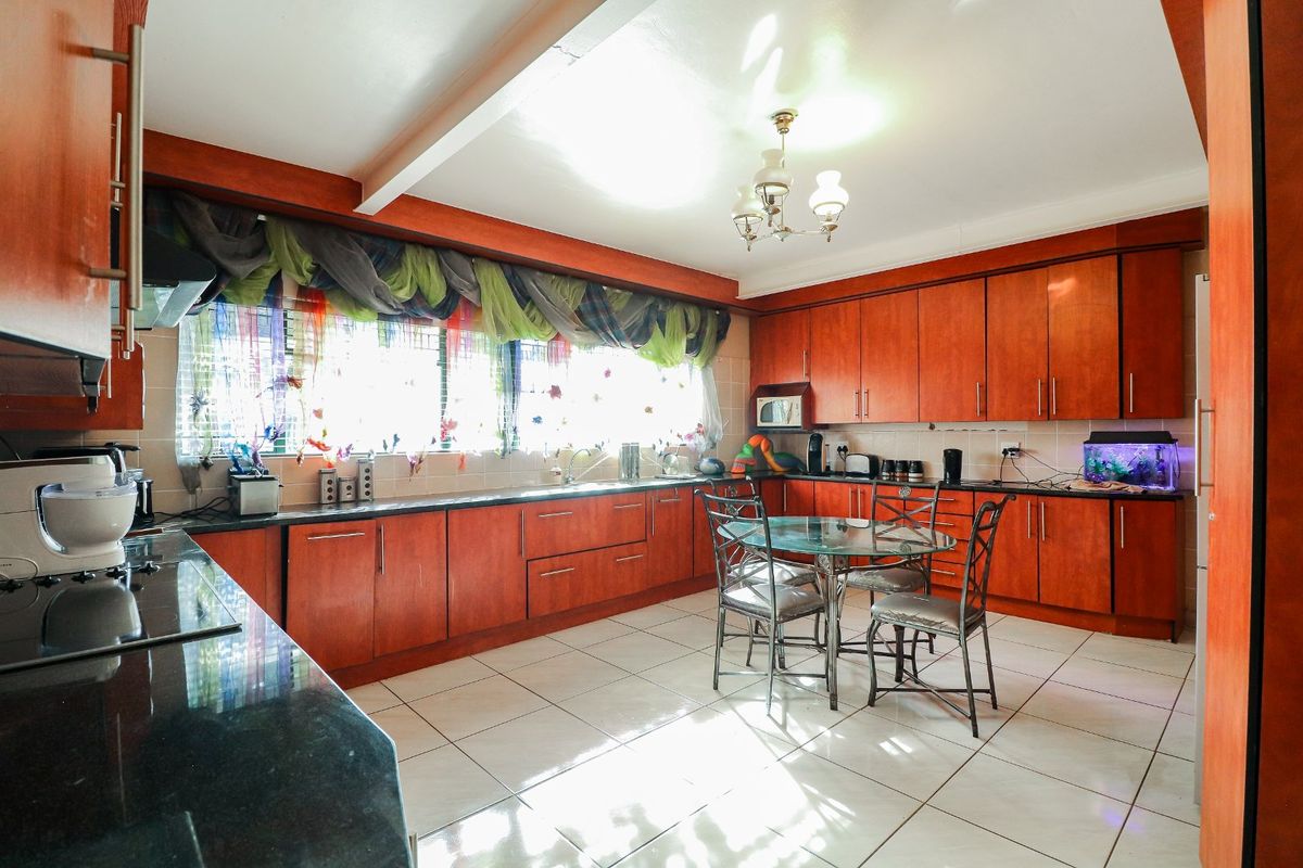 Spacious kitchen featuring extensive wood-finish cabinetry, granite countertops, tiled flooring, and integrated appliances, offering a functional layout with ample storage and workspace.