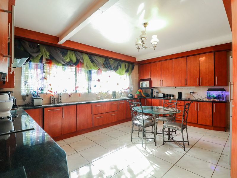 Spacious kitchen featuring extensive wood-finish cabinetry, granite countertops, tiled flooring, and integrated appliances, offering a functional layout with ample storage and workspace.