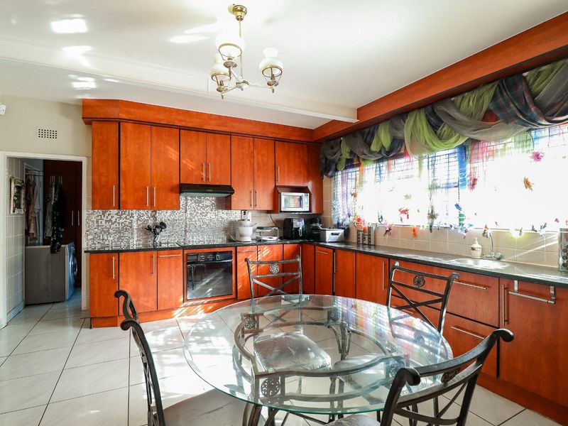 A functional kitchen featuring warm-toned wooden cabinetry, a mosaic tile backsplash, integrated appliances, and tiled flooring, offering a classic layout with ample storage space.