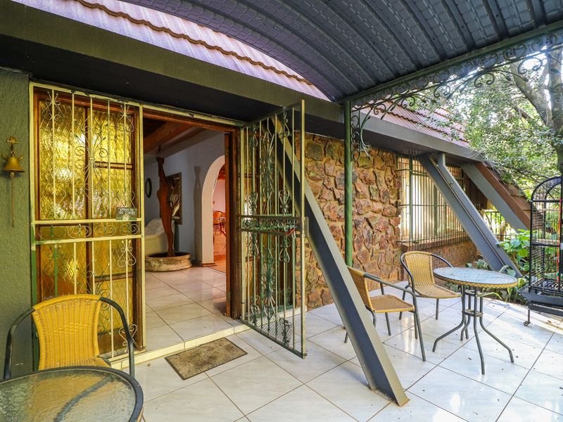 Covered patio area featuring tiled flooring, stone wall accents, and a curved metal roof structure, providing a sheltered outdoor space.