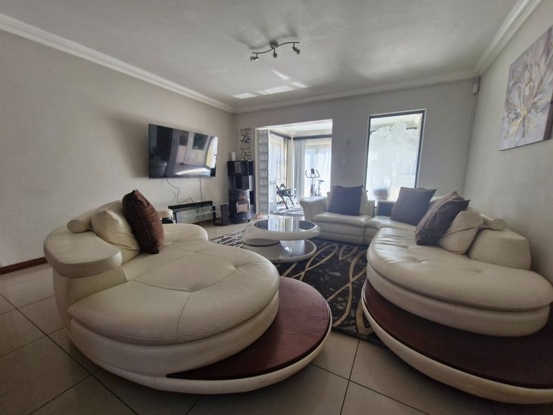 Spacious living room featuring tiled flooring, coved ceilings, and large sliding glass doors that provide access to an adjoining patio area.