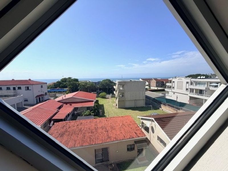 A clear elevated view of the surrounding residential neighborhood and distant ocean horizon framed by a diamond-shaped window.
