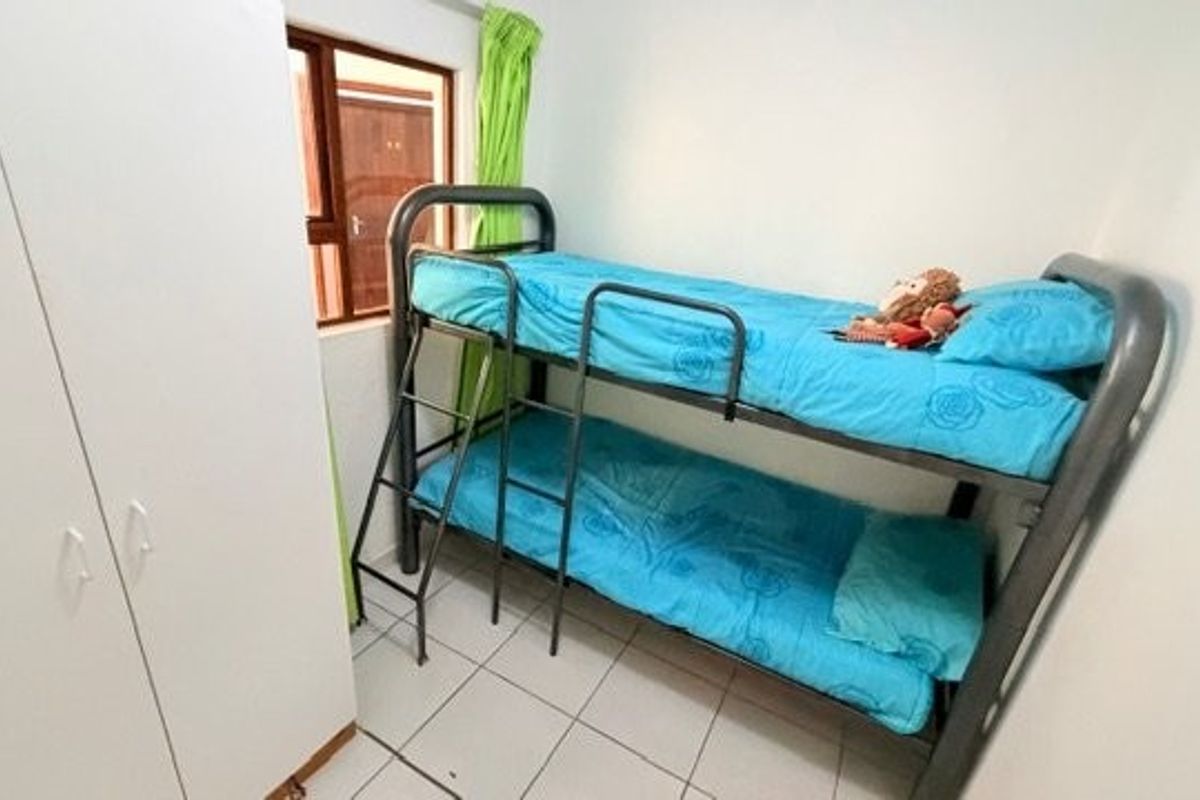 A compact bedroom featuring tiled flooring and a built-in wardrobe, providing functional storage space.